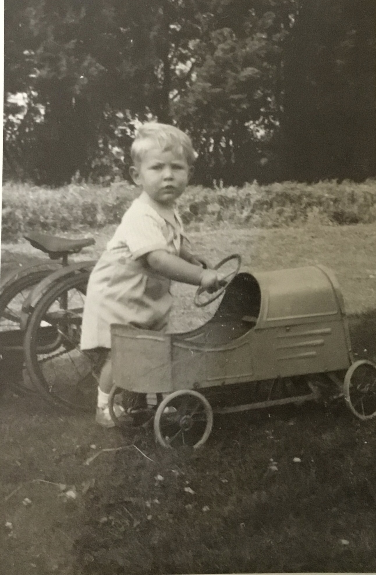 A young John playing with a pedal car.